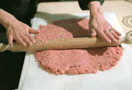 На великий аркуш паперу для випічки викласти м'ясний фарш і розкачати качалкою в прямокутник товщиною приблизно 1 см